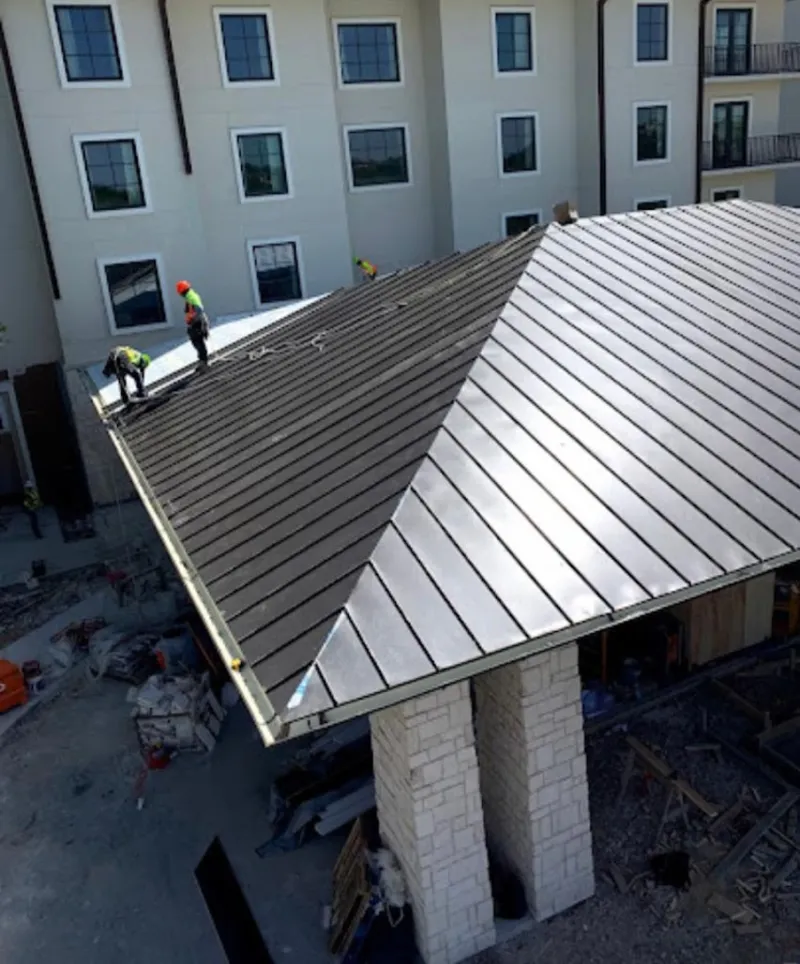 Crew installing standing seam metal roof panels on a commercial project in Port Allen